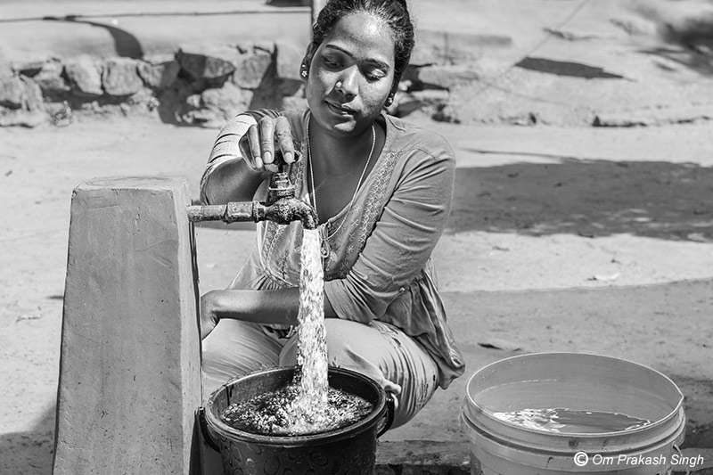 A young woman in a rural home in Khunti district, Jharkhand, uses a functional household tap from Jal Jeevan Mission, illustrating the convenience of uninterrupted daily water access at home.